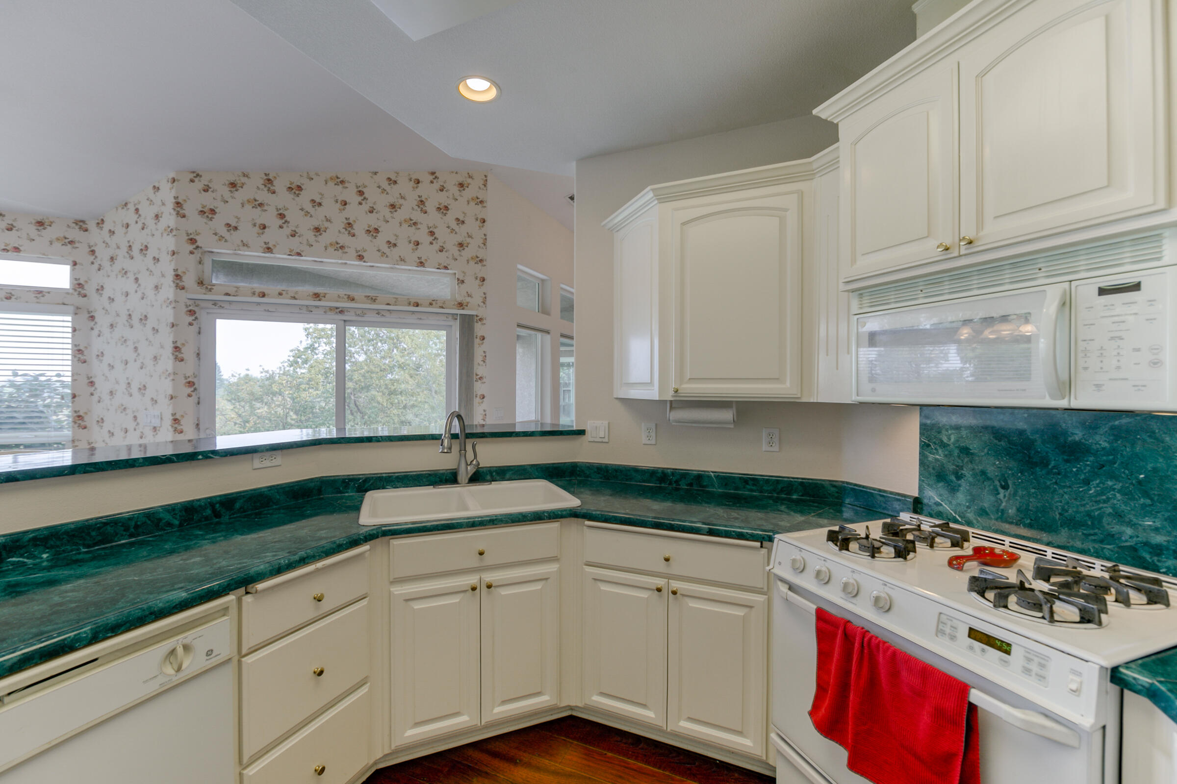 2965 Shadow Brook Lane Redding, CA 96001 - Photo 15 of 38 a kitchen with granite countertop a stove a sink and white cabinets