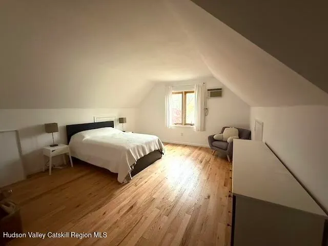 a spacious bedroom with a bed and wooden floor