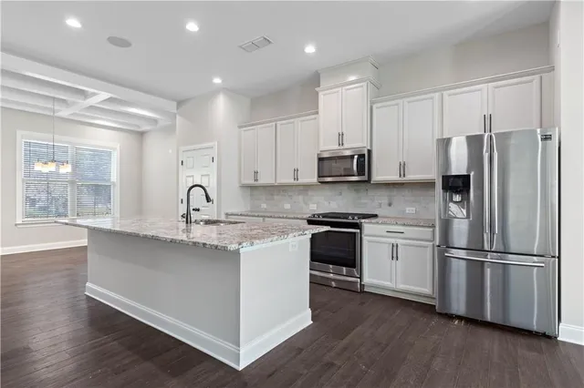 a kitchen with stainless steel appliances granite countertop a refrigerator a sink dishwasher a stove and white cabinets with wooden floor