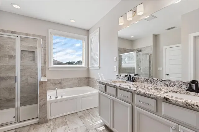 a bathroom with a granite countertop tub sink shower and mirror