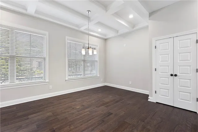 an empty room with wooden floor cabinet and windows