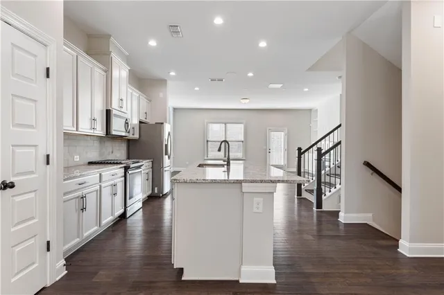 a kitchen with stainless steel appliances granite countertop wooden floors and white cabinets