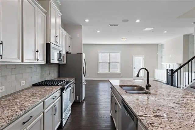 a kitchen with granite countertop a sink stainless steel appliances and cabinets