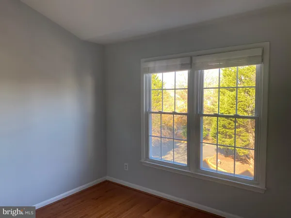 a view of an empty room and wooden floor and a window