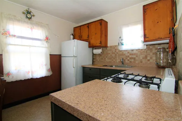 a kitchen with a refrigerator a stove a sink a counter top space and cabinets