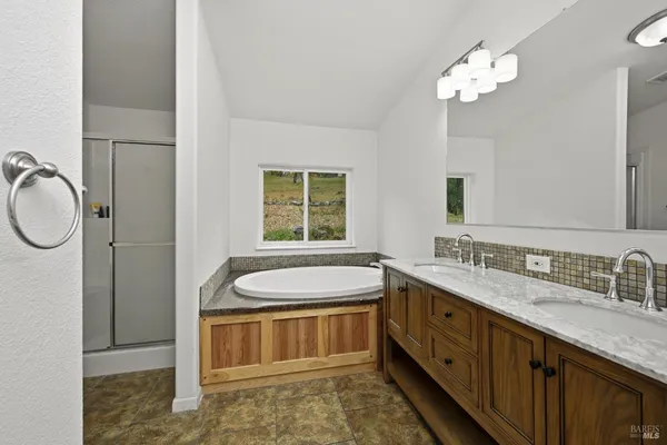 a spacious bathroom with a double vanity sink a mirror a and a window