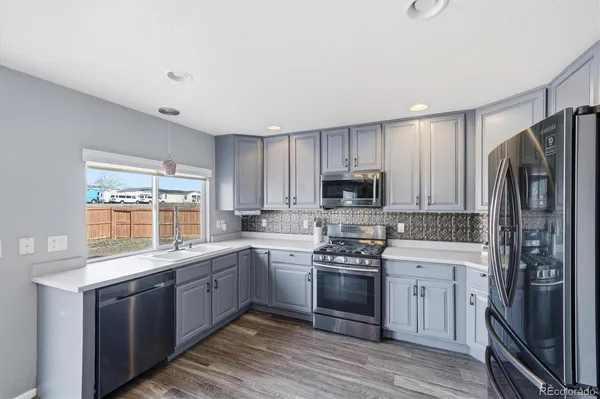 a kitchen with stainless steel appliances granite countertop a stove a sink dishwasher a refrigerator and a microwave oven with wooden floor