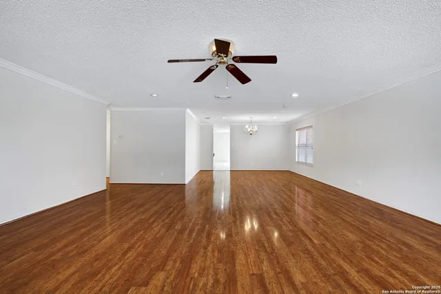 a view of empty room with wooden floor and ceiling fan