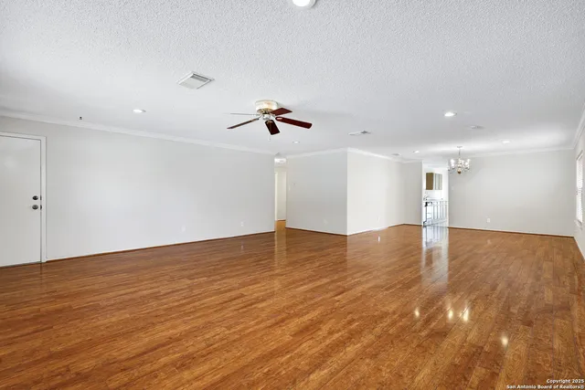 a view of empty room with wooden floor and ceiling fan