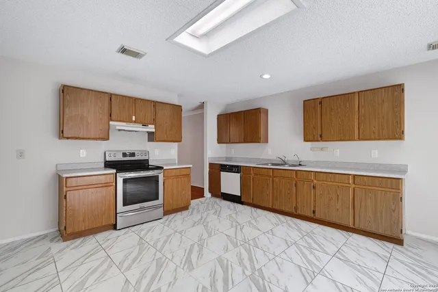 a kitchen with granite countertop a stove top oven microwave and cabinets