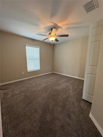 an empty room with windows and fan