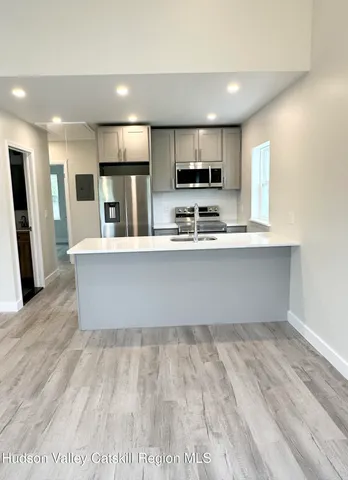 a large white kitchen with stainless steel appliances kitchen island a large counter top and wooden floors