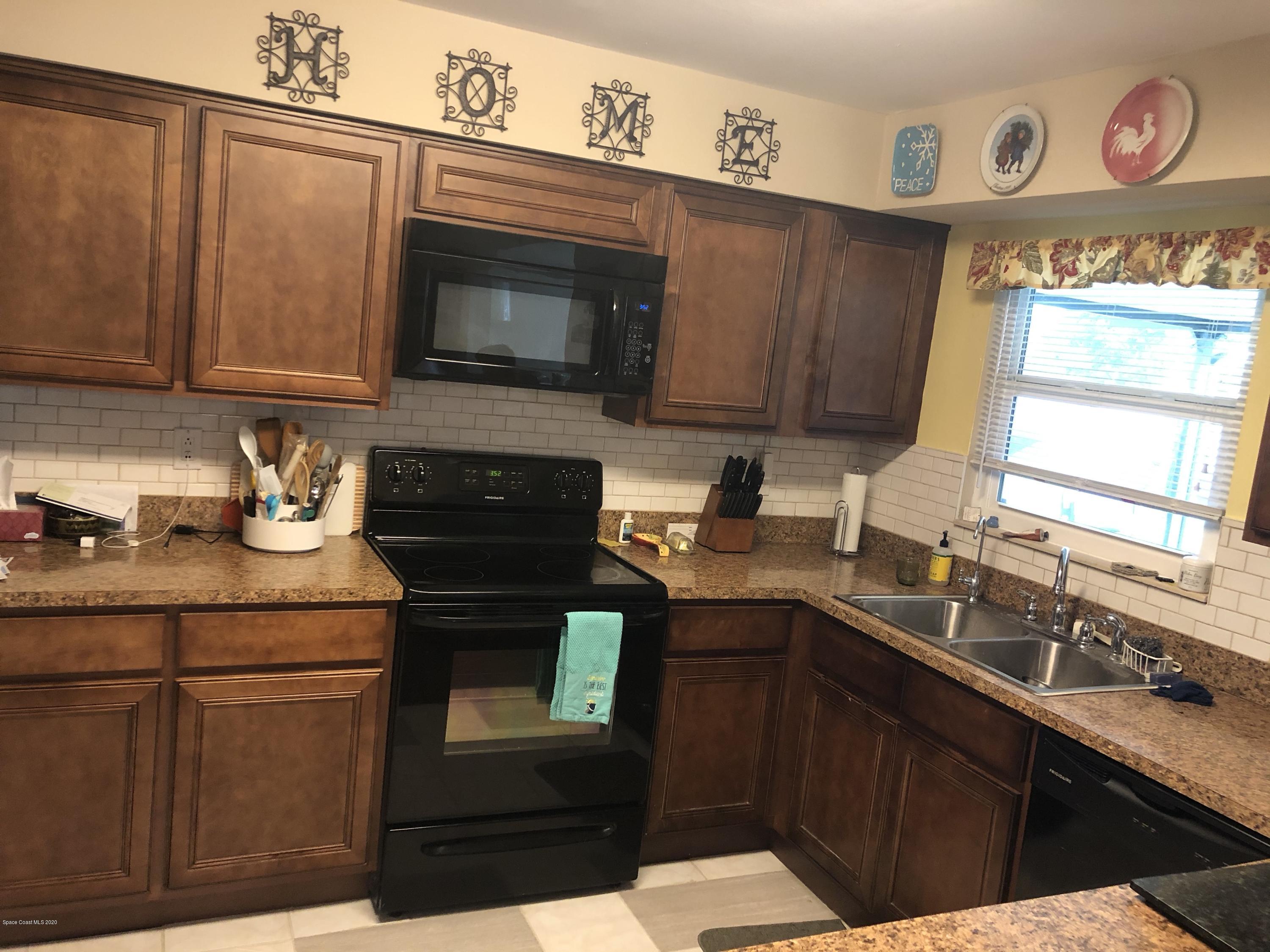 1491 Creel Road Northeast Palm Bay, FL 32905 - Photo 3 of 50 a kitchen with granite countertop a sink stove and microwave