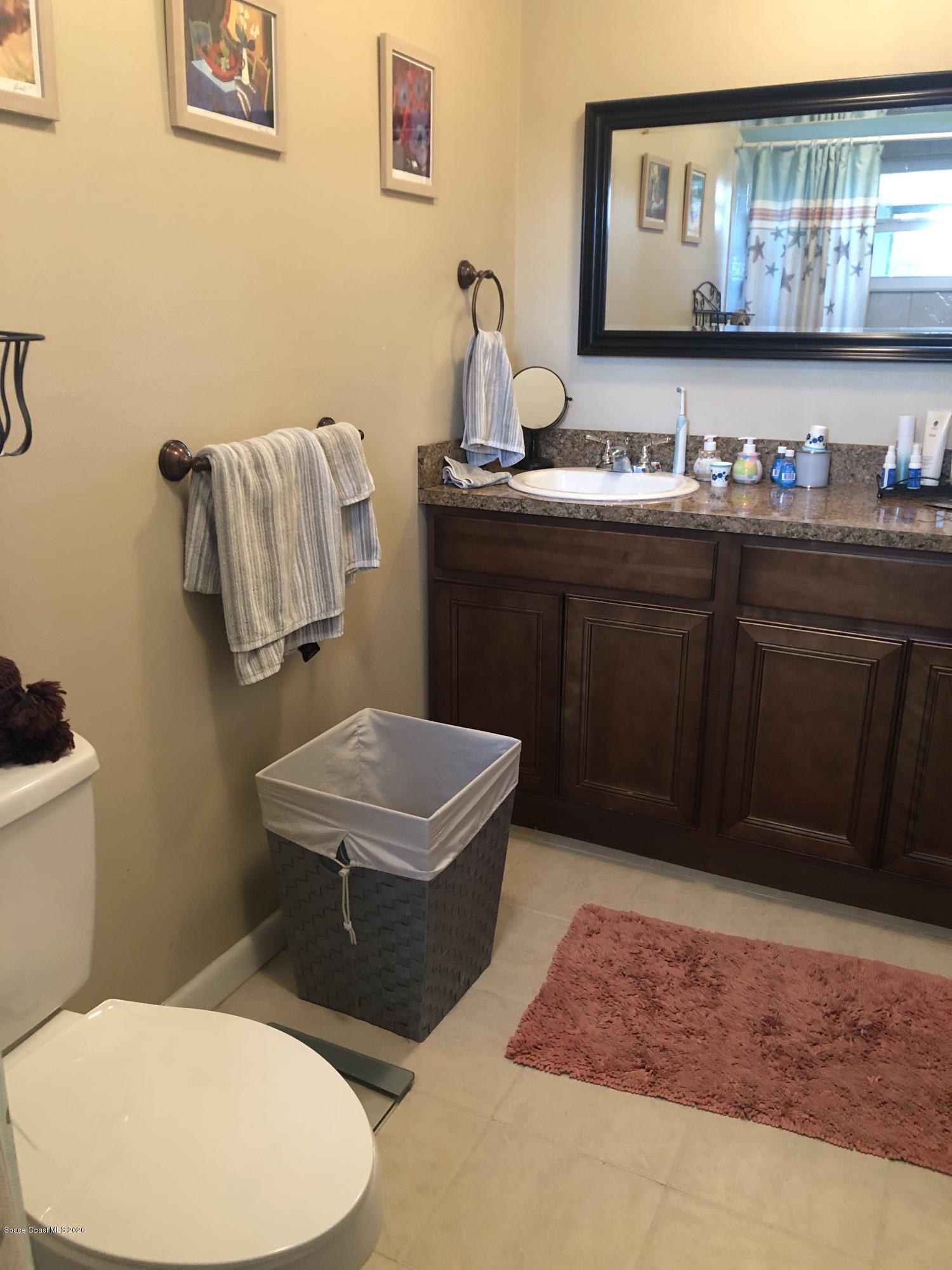 1491 Creel Road Northeast Palm Bay, FL 32905 - Photo 7 of 50 a bathroom with a sink a toilet and mirror