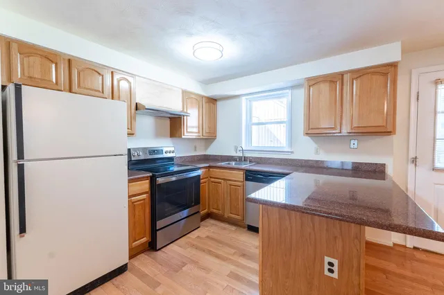 a kitchen with granite countertop a refrigerator stove top oven and sink