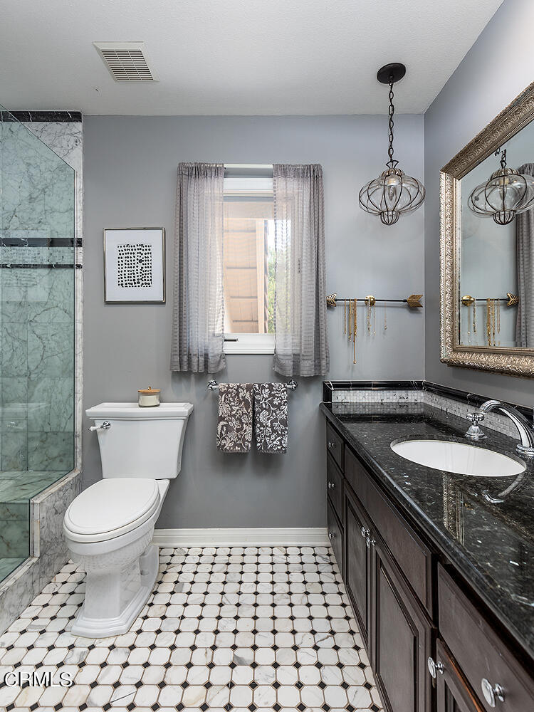1429 Rutherford Drive Pasadena, CA 91103 - Photo 22 of 34 a bathroom with a granite countertop toilet a sink a mirror a window and a shower