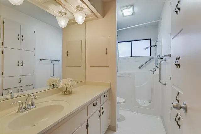 a bathroom with a granite countertop sink a toilet and shower
