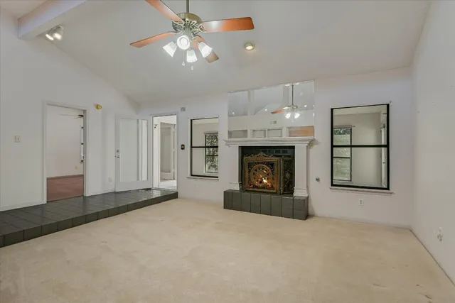 an empty room with windows and fireplace