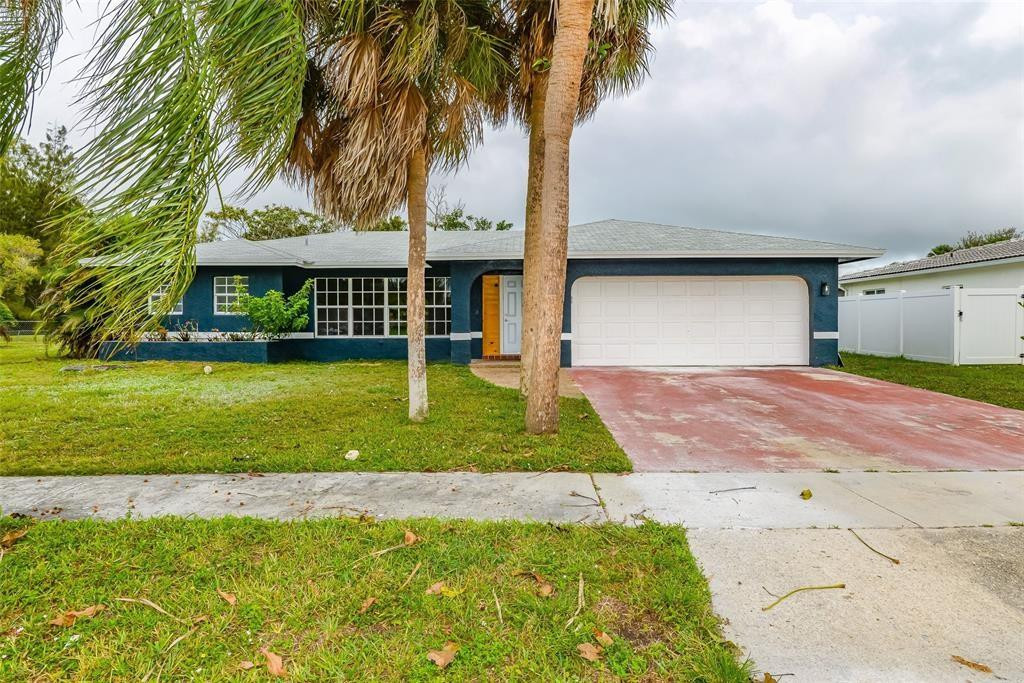 a front view of a house with a yard and palm trees