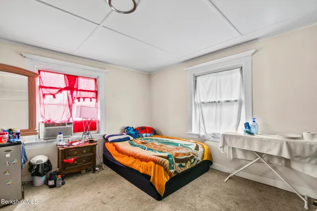 a bedroom with a bed a window and dresser