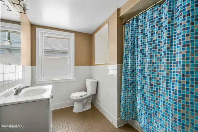 a bathroom with a granite countertop toilet a sink and mirror