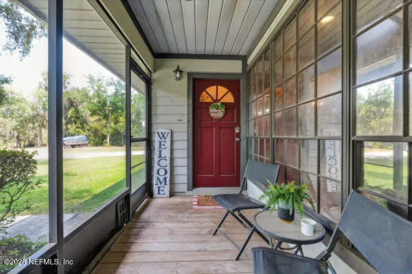 a porch with a table and chairs next to a yard