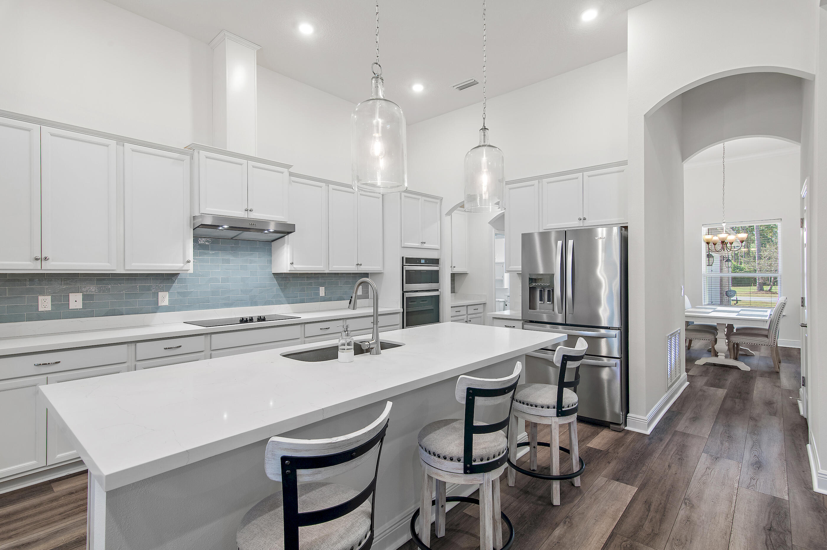 588 Windswept Boulevard Freeport, FL 32439 - Photo 12 of 62 a kitchen with stainless steel appliances a stove a sink a refrigerator and white cabinets with wooden floor
