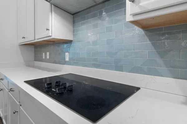 a kitchen with stainless steel appliances a stove a sink a refrigerator and white cabinets with wooden floor