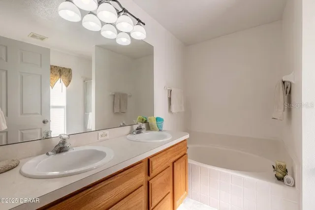 a bathroom with a sink double vanity granite tub shower and a mirror
