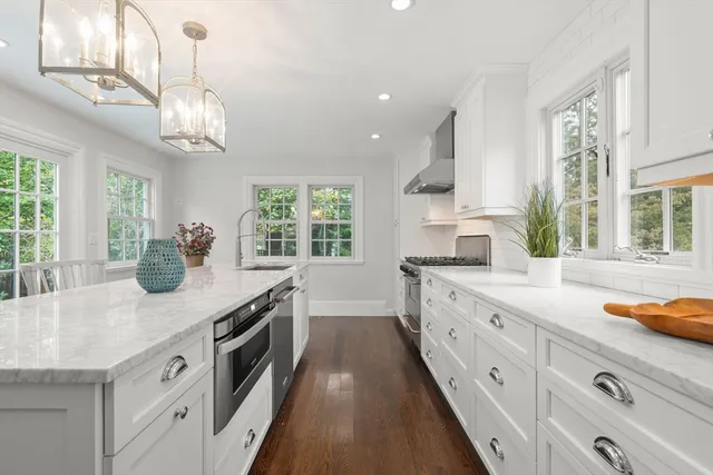 a kitchen with stainless steel appliances granite countertop a white stove a sink dishwasher and white cabinets with wooden floor