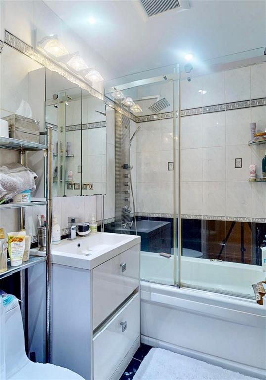 2546 East 13th Street, Unit L14 Brooklyn, NY 11235 - Photo 4 of 10 a bathroom with a double vanity sink a mirror and shower