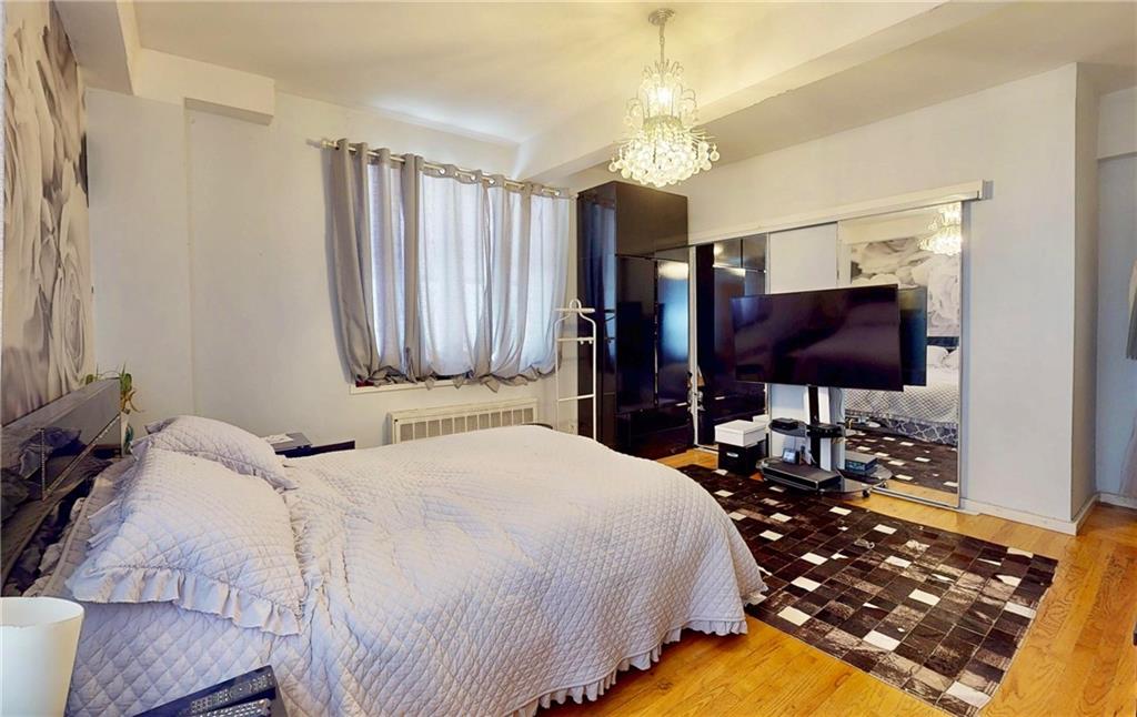 2546 East 13th Street, Unit L14 Brooklyn, NY 11235 - Photo 6 of 10 a bedroom with a bed and a chandelier