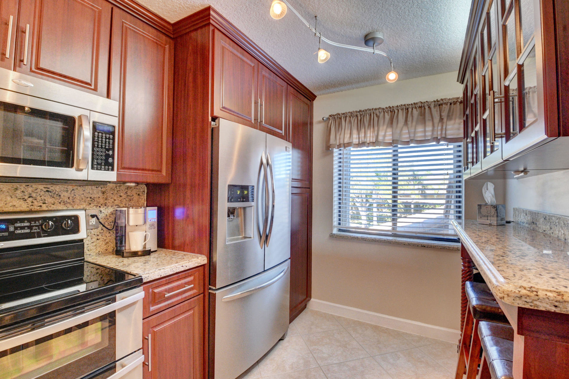 210 Captains Walk, Unit 710 Delray Beach, FL 33483 - Photo 12 of 49 a kitchen with stainless steel appliances granite countertop a refrigerator a stove and a sink