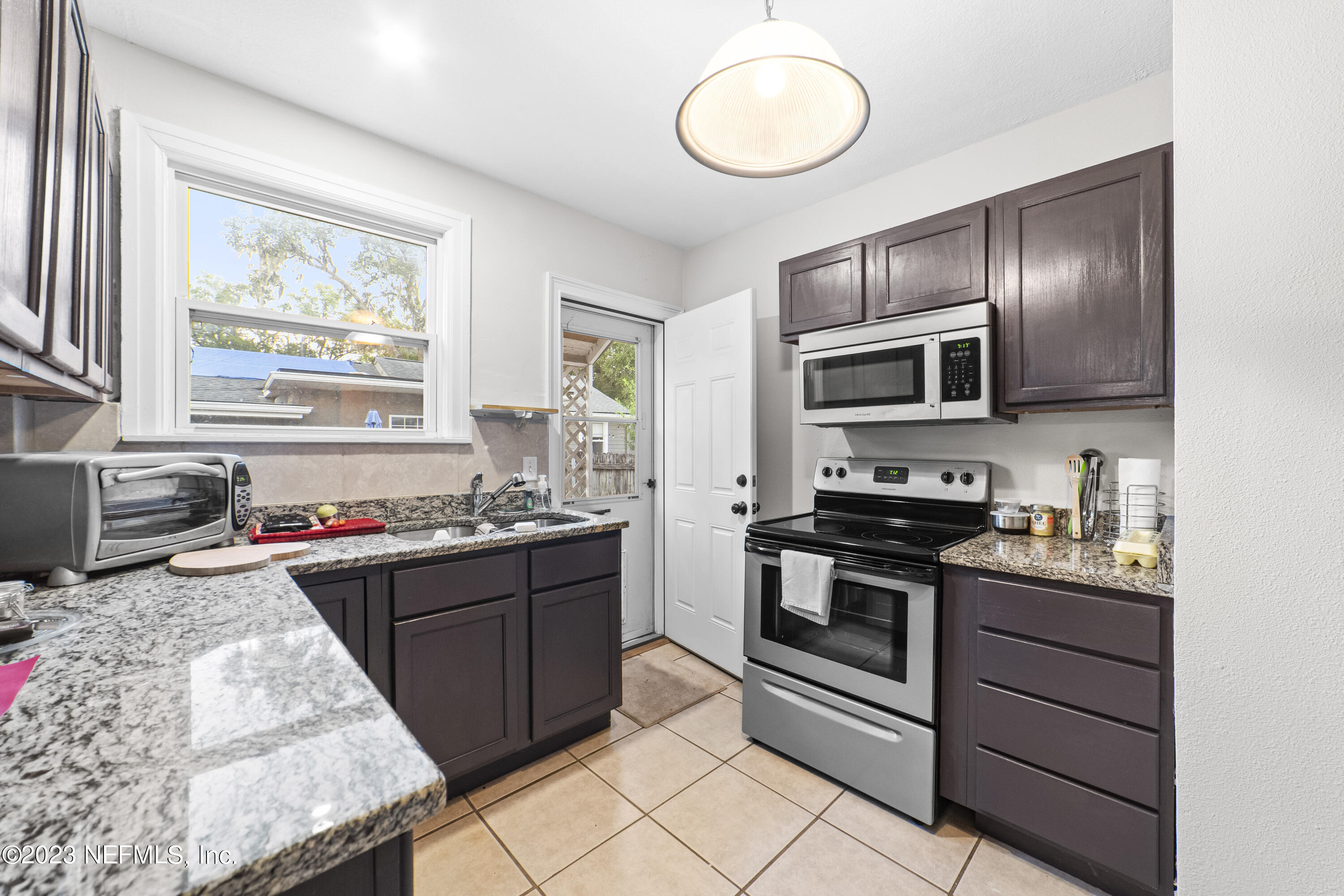 1719 Mayfair Road Jacksonville, FL 32207 - Photo 9 of 14 a kitchen with stainless steel appliances granite countertop a stove top oven a sink dishwasher a dining table and chairs with wooden floor