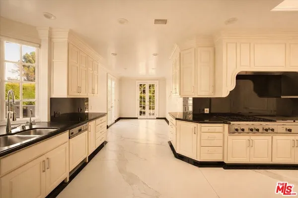 a kitchen with granite countertop white cabinets and sink