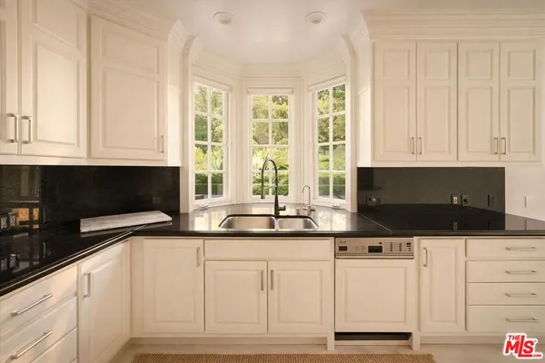 a kitchen with granite countertop white cabinets and stainless steel appliances