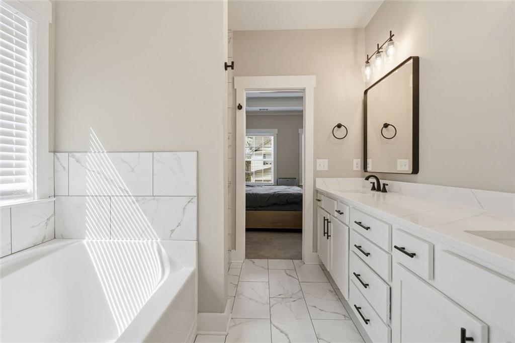 241 Bethany Manor Court Ball Ground, GA 30107 - Photo 26 of 36 a bathroom with a tub sink and mirror