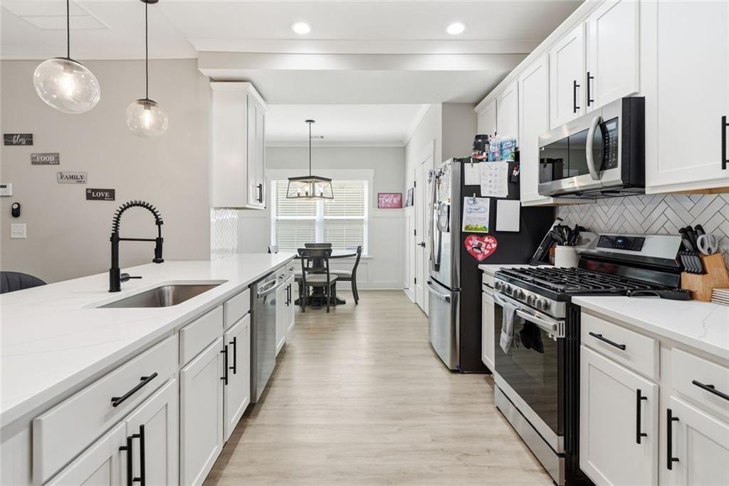 241 Bethany Manor Court Ball Ground, GA 30107 - Photo 10 of 36 a kitchen with stainless steel appliances a sink dishwasher stove refrigerator and cabinets with wooden floor