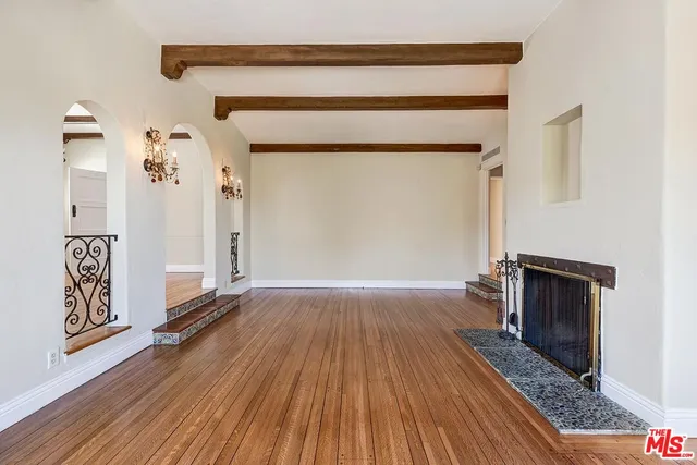 an empty room with wooden floor fireplace and windows