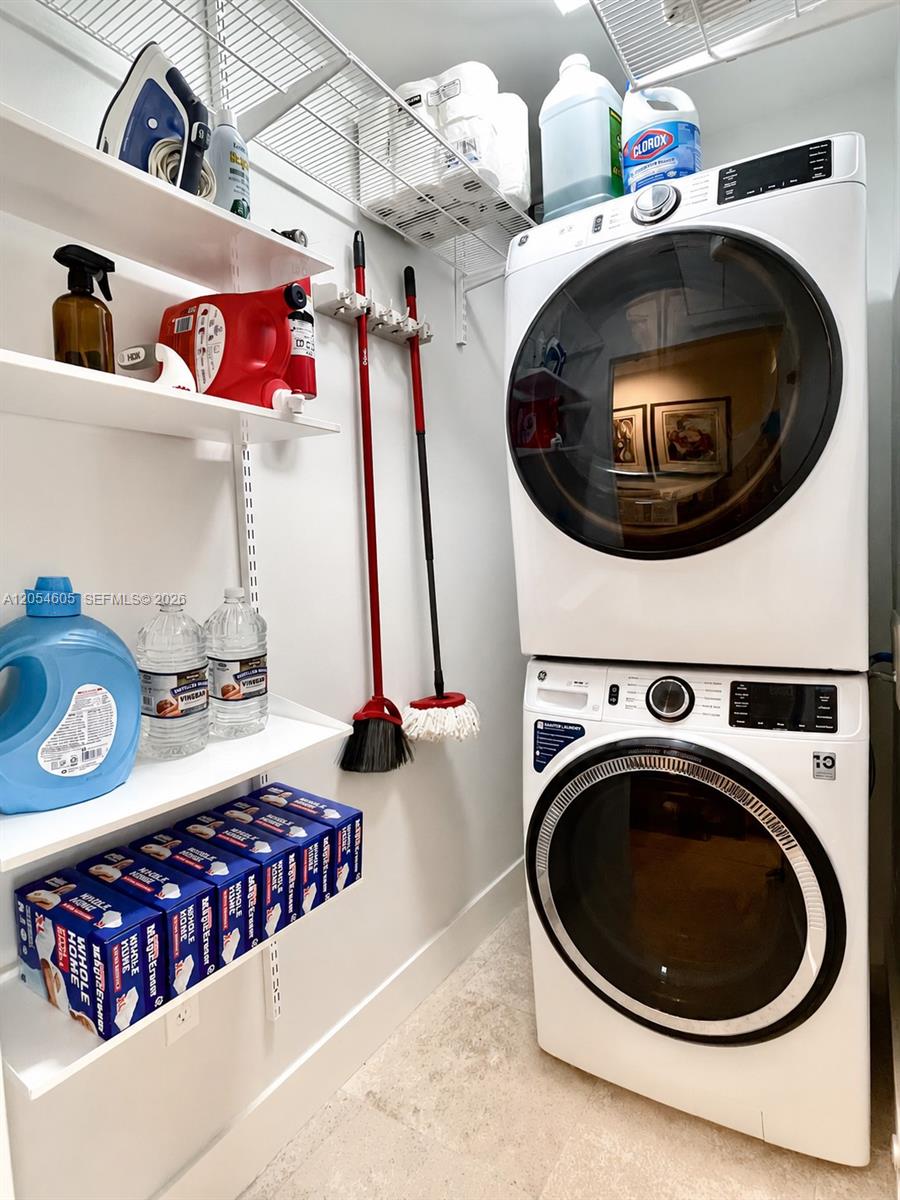 3538 Southwest 1st Avenue, Unit 1 Miami, FL 33145 - Photo 17 of 20 Bright and functional laundry room featuring a stacked washer and dryer, extensive open shelving, overhead wire storage, and dedicated space for cleaning supplies and household essentials. The organized layout maximizes storage while keeping everything easily accessible in a clean, efficient setting.