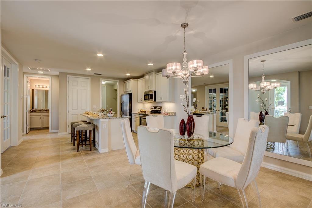 14533 Edgewater Circle Naples, FL 34114 - Photo 8 of 24 a dining room with furniture a chandelier and kitchen view