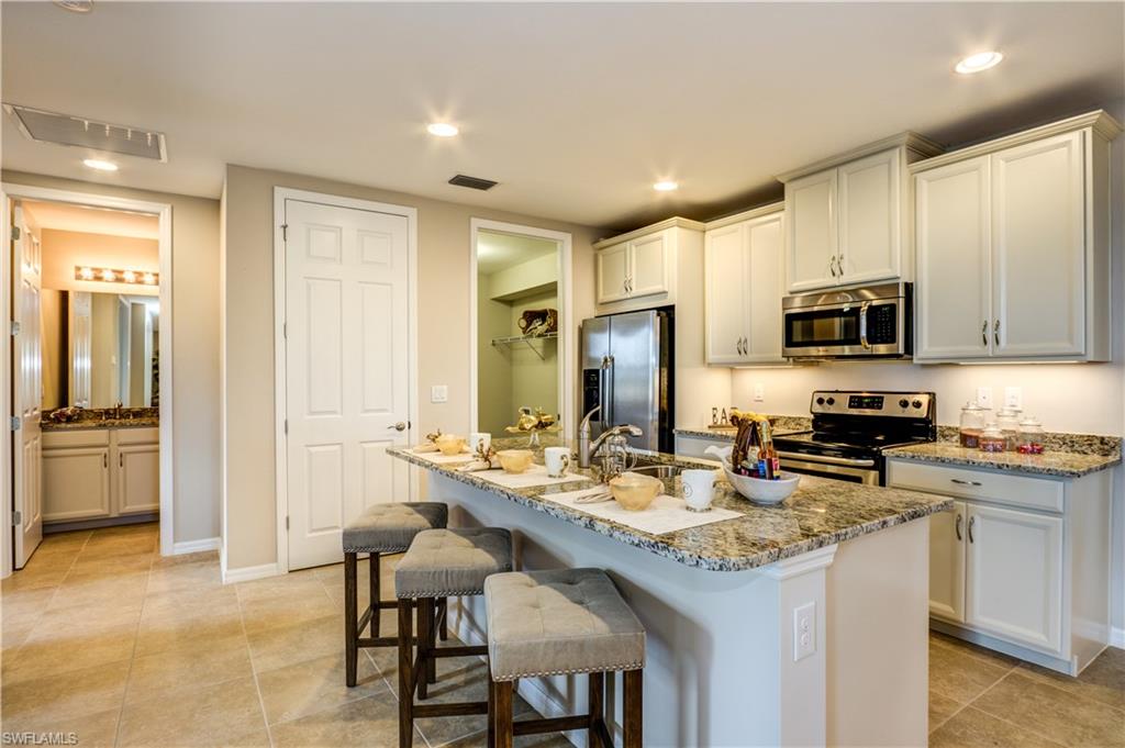 14533 Edgewater Circle Naples, FL 34114 - Photo 10 of 24 a kitchen with sink cabinets and stainless steel appliances