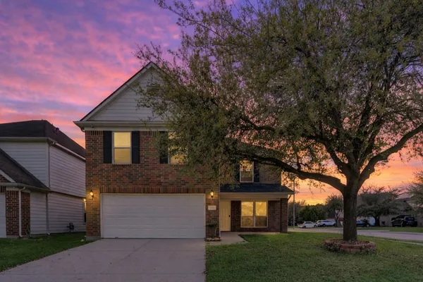 a front view of a house with a garden and trees