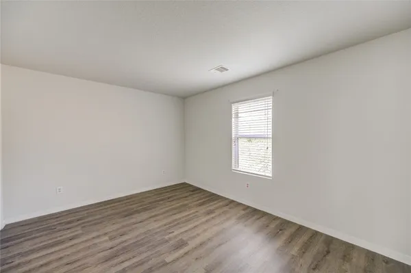 an empty room with wooden floor and window