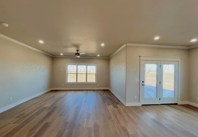 an empty room with wooden floor and windows