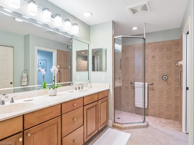 a bathroom with a double vanity sink mirror and shower
