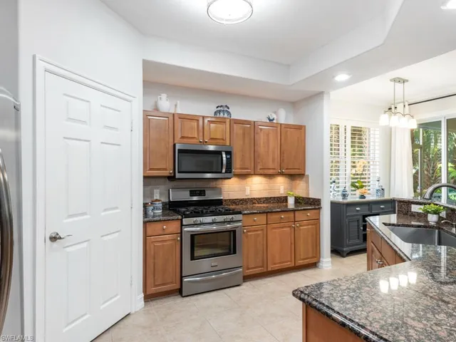 a kitchen with stainless steel appliances granite countertop a stove top oven a sink dishwasher a dining table and chairs with wooden floor