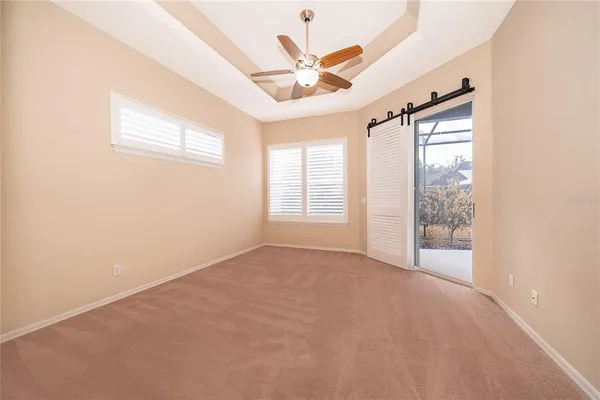 an empty room with windows and ceiling fan
