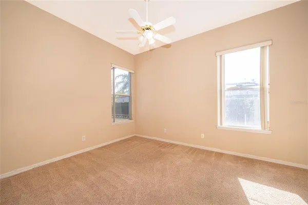 an empty room with windows and fan