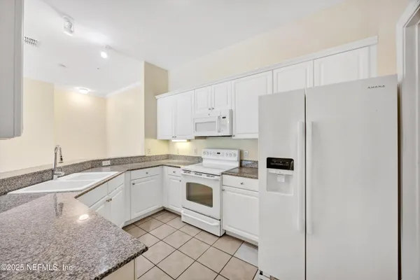 a kitchen with granite countertop stainless steel appliances white cabinets granite counter tops and a sink